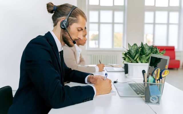 man in black suit jacket writing on a paper