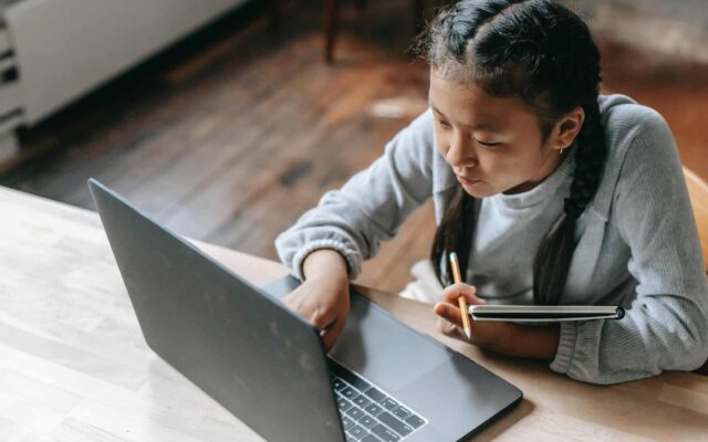focused young asian girl studying on wireless laptop