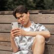 asian displeased man browsing smartphone in countryside