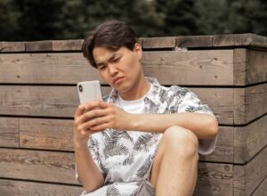 asian displeased man browsing smartphone in countryside
