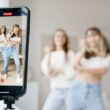 woman in white sleeveless shirt and blue denim skirt holding black smartphone