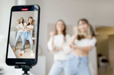 woman in white sleeveless shirt and blue denim skirt holding black smartphone