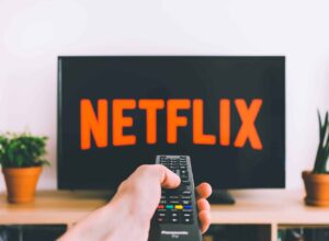 closeup photo of person holding panasonic remote control in front of turned on smart television