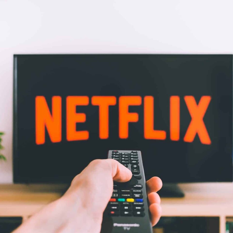 closeup photo of person holding panasonic remote control in front of turned on smart television
